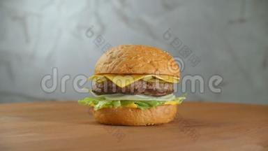 一个汉堡包在一块板上，炸薯条散落一地。特写美味的新鲜自制汉堡配生菜、奶酪